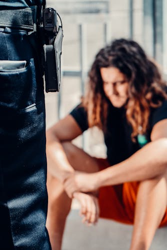 Person in custody sitting on street waiting for police next steps