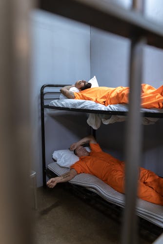 Two cellmates sharing a bunk bed in a prison cell